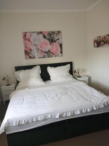 a bed with white sheets and pink roses on the wall at Villa Rosali Boutique Hotel in Hamburg