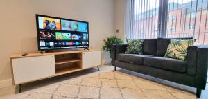 a living room with a couch and a flat screen tv at Seven Living Residences Slough - City Apartments, Free Parking in Slough