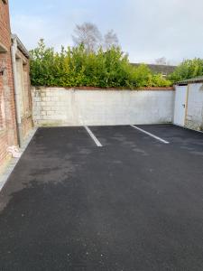 un estacionamiento junto a una pared de ladrillo en Appartement Familial - Avec Parking Privé Gratuit, en Arras