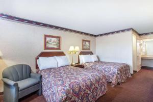 una stanza d'albergo con due letti e una sedia di Days Inn by Wyndham Saint Pauls a Saint Pauls