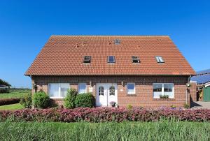 a brick house with a red roof at Ferienwohnungen auf dem Ferienhof Elke Peters in Holtgast
