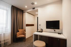 a room with a desk with a tv and a chair at Victoria Palas Hotel in Astrakhan