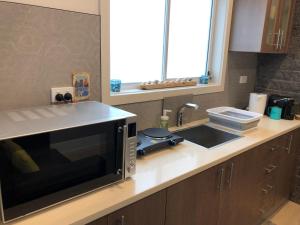 a kitchen counter with a microwave and a sink at STUDIO RETREAT BY THE BEACH in Rye