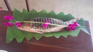 a fish on a banana leaf with flowers on it at African Ecolodge Angurman in Bruce