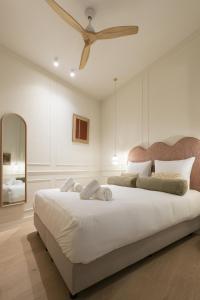 a bedroom with a large white bed with a ceiling fan at Le Lambermont in Antwerp