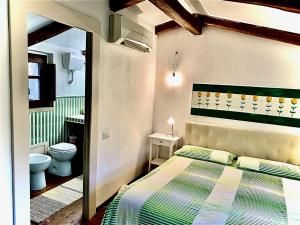 a bedroom with a bed and a bathroom with a toilet at -- La Maisonette Casa Vacanze by Le Dimore del Borgo -- Graziosa casa a due passi dal parco Aymerich - Cucina - Dotazione biancheria - Tutti i comfort - Privacy libertà come stare a casa -Per coppie famiglie amici - Holiday Home with Kitchen in Làconi
