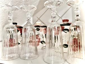 three glass wine glasses sitting on top of a counter at -- La Maisonette Casa Vacanze by Le Dimore del Borgo -- Graziosa casa a due passi dal parco Aymerich - Cucina - Dotazione biancheria - Tutti i comfort - Privacy libertà come stare a casa -Per coppie famiglie amici - Holiday Home with Kitchen in Làconi +29 photos
