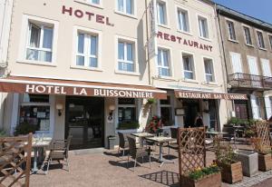 a hotel with tables and chairs in front of a building at La Buissonnière in Corbigny