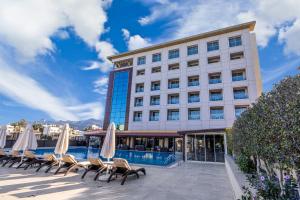 a hotel with chairs and umbrellas next to a pool at Grand Pasha Hotel & Spa Kyrenia in Kyrenia