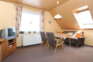 a living room with a table and a couch and a tv at Ferienwohnungen auf dem Ferienhof Elke Peters in Holtgast