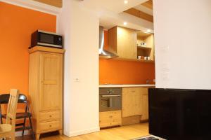 ボルゴにあるTrentino Apartments - Il Gufo Vacanzeのオレンジ色の壁と木製のキャビネット、テレビが備わるキッチン