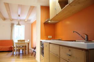 cocina con paredes de color naranja, fregadero y mesa en Trentino Apartments - Il Gufo Vacanze, en Borgo