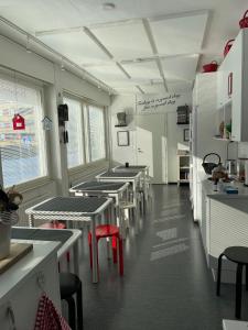 a row of tables in a kitchen with red chairs at Tapulitalo Guesthouse in Turku