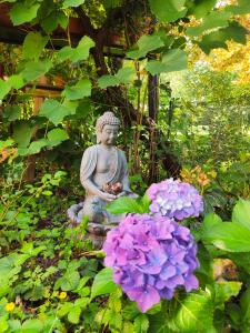 uma estátua num jardim com flores roxas em Modernes Zimmer am Park mit Garten, Hühner & Enten em Munique