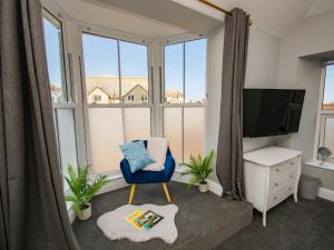 a living room with a blue chair and a large window at Daniel Chambers in Camborne