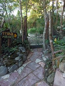 a garden with a sign and a stone path at CASA DA MATA descanso e sossego na natureza in Ibicoara