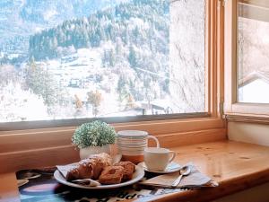 a table with a plate of pastries and a window at Dolomiti Relax Home in Perarolo di Cadore