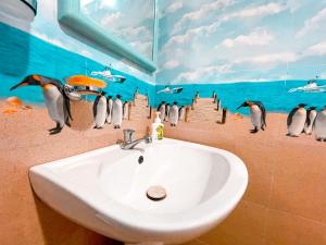 a bathroom with a sink and penguins on the wall at Coco Mount Mirissa in Matara