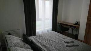 a bedroom with a bed and a desk and a window at Apartamenty Color - Niebieski in Kielce