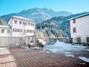 a brick courtyard in front of two buildings with mountains at Dolomiti Relax Home in Perarolo di Cadore