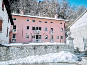 a pink building with snow in front of it at Dolomiti Relax Home in Perarolo di Cadore