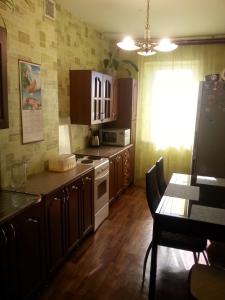 uma cozinha com armários de madeira e uma mesa com mesa; em Квартира у Светы em Pitsunda