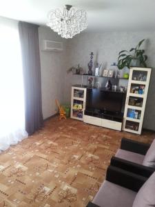 a living room with a television and a wooden floor at Квартира у Светы in Pizunda
