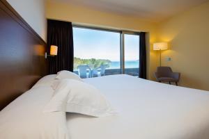 a hotel room with a bed and a large window at Hotel Thalasso Cantabrico Las Sirenas in Viveiro
