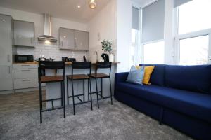 a living room with a blue couch and a kitchen at Affinity Serviced Apartments by SSW in Cardiff