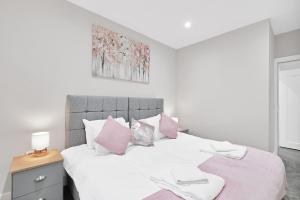 1 dormitorio con cama blanca y almohadas rosas en Crown Place 2 & 3 Bedroom Luxury Apts with Parking in Shepperton By 360Stays, en Shepperton