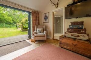 a living room with a tv and a chair and luggage at The Lodge, Wherstead 