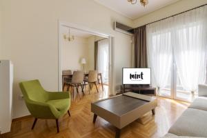 a living room with a green chair and a tv at Minimal 2 bedroom apt near the Athens Concert Hall in Athens