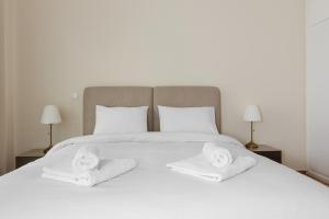 a white bed with two towels and two lamps at Minimal 2 bedroom apt near the Athens Concert Hall in Athens