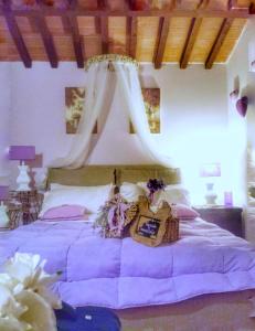 ein Schlafzimmer mit einem großen lila Bett mit Baldachin in der Unterkunft Piccolo Relais Galletto di Marzo Spa e relax solo per due in Paciano