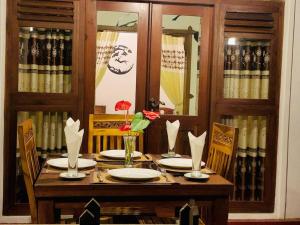 a wooden table with plates and flowers on it at Ella Sandy Heaven Homestay in Ella