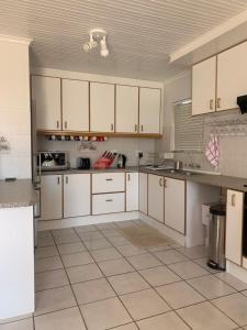 a kitchen with white cabinets and a tile floor at 5 bedroom home in Langebaan, located close to Club Mykanos and Laguna Mall in Langebaan