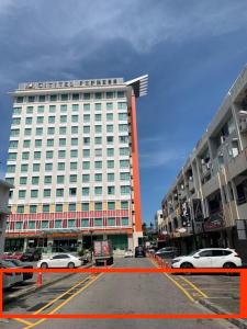 a large white building with cars parked in a parking lot at ACJ Residence @ Beside Cititel Hotel in Kota Kinabalu