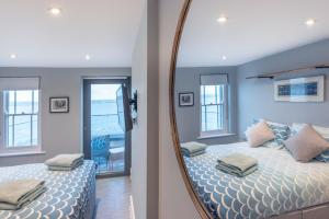 a mirror reflecting a bedroom with a bed with blue walls at The Royal George in Appledore