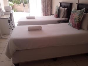 duas camas num quarto de hotel com lençóis brancos em Kuyasa guesthouse em Mthatha