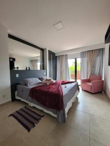 a bedroom with a large bed and a pink chair at Flats Baia dos Porcos in Fernando de Noronha +75 photos