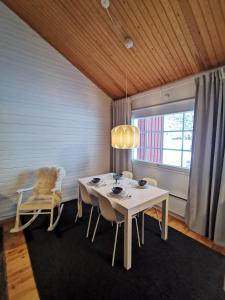 a dining room with a white table and a window at Winter Nest - A cozy accommodation in the heart of Saariselkä in Saariselka