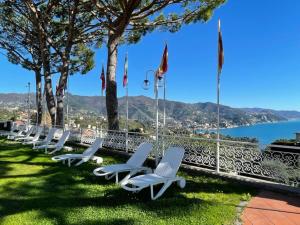 une rangée de chaises blanches assises sur l'herbe près de l'eau dans l'établissement Portofino Est Residence, à Rapallo