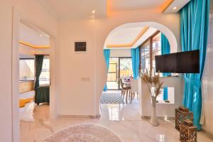 a living room with blue curtains and a flat screen tv at Flower Hotel Patara in Patara