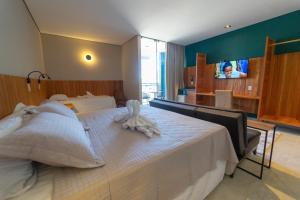 a bedroom with a large bed with a tv on the wall at Hotel da Praça in Bonito
