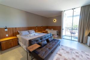 a bedroom with a bed and a couch at Hotel da Praça in Bonito