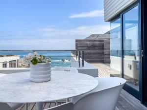 a white table with a vase of flowers on a balcony at Le Paradis Penthouse in Hermanus +41 photos