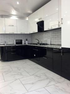 een witte keuken met zwarte kasten en witte tegels bij VIP апартаменты 2 ком в центре ЖК Жуковский in Dnipro