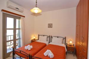 a bedroom with two beds with orange sheets and a window at To Pithari in Skiros