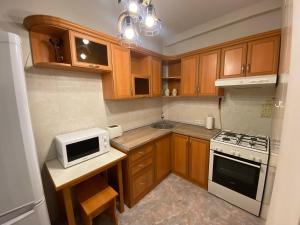 uma pequena cozinha com armários de madeira e um micro-ondas em Northern Avenue Apartment em Yerevan