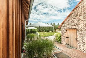 a patio with an umbrella and chairs and a door at Boerderaaj in Bilzen